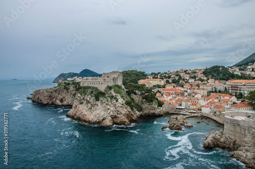 View of city walls of Dubrovnik and blue sea, Dubrovnik, Croatia. Dubrovnik old town surrounded by old walls. View from above of red rooftops, roofs and fortress.