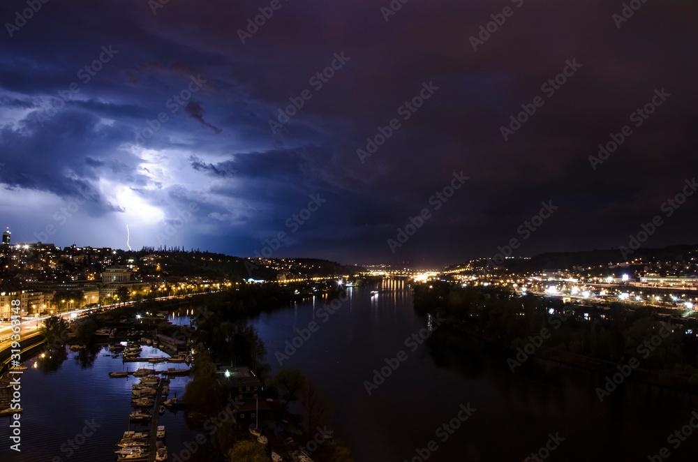 River and lightning on the sky during summer thunderstorm at night in Prague, Czech republic. Night view of Prague. Beautiful cloudy sky