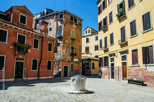Yard with a well and colorful buildings in Venice, Italy. Italian square with colorful buildings in Venice