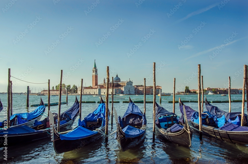 Gondolas pier row anchored on Canal Grande with San Giorgio Maggiore church in the background, Venice, Italy