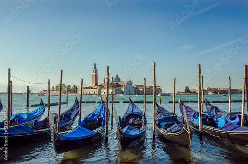 Gondolas pier row anchored on Canal Grande with San Giorgio Maggiore church in the background, Venice, Italy © Maria Vonotna
