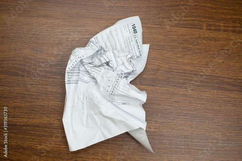 USA IRS tax form 1040 crumpled on a wooden table. Concept for frustration, difficulty and needing help in understanding tax laws and regulations