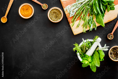 Herbs and spices on black kitchen desk top-down copy space