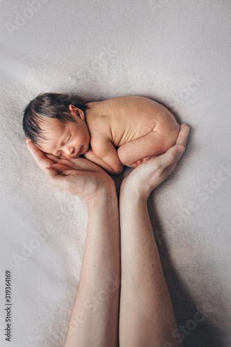 Newborn baby lying on hands of parents. Imitation of baby in womb. beautiful little girl sleeping on her back. manifestation of love. Health care concept, parenthood, children's Day, medicine, IVF