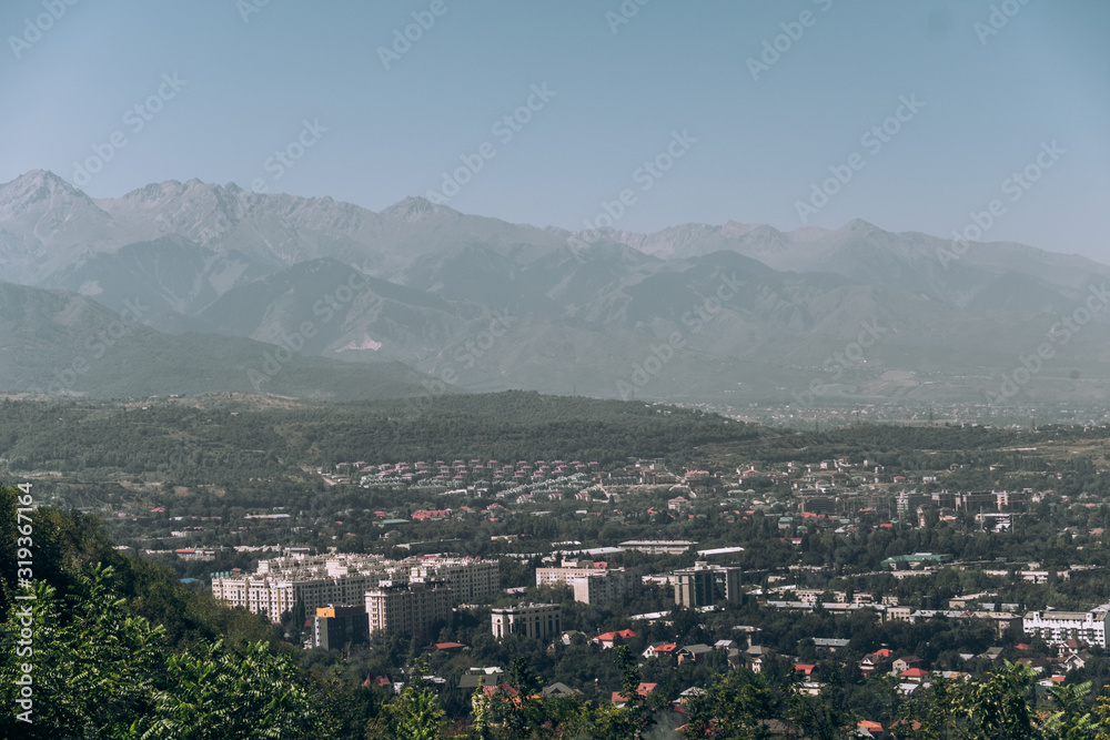 Kazakhstan. View of the city of Almaty. Summer, sunny weather. Tall buildings on a background of mountains