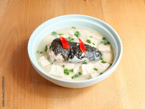 Close up of milky fish head soup in bowl on table, traditional Chinese delicious food. photo