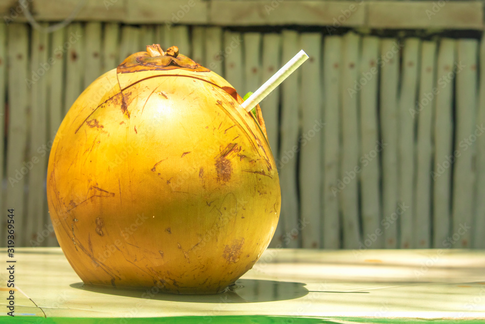 Whole fresh yellow coconut on the sunny day at island on authentic background
