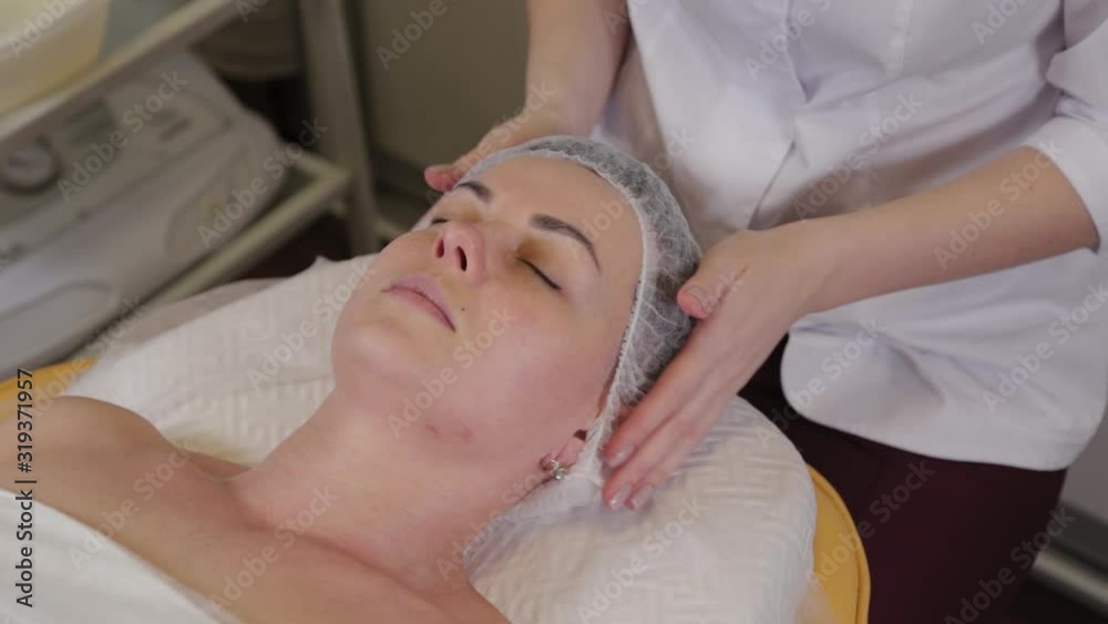 Professional beautician washes face to patient before face cleaning procedure.