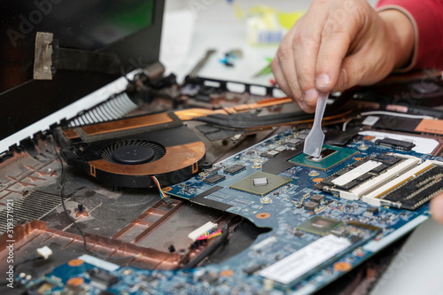 the master applies thermal grease to the computer processor. Notebook with replacement thermal paste.