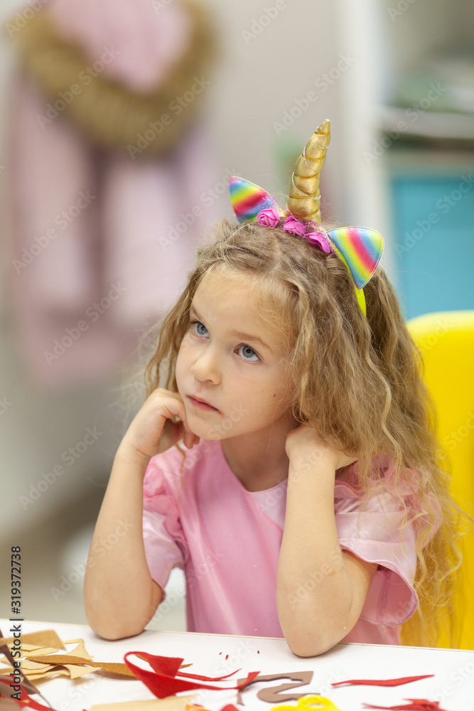 Pretty little girl sits at a table and dreams, portrait Pretty little girl sits at a table and dreams, portrait