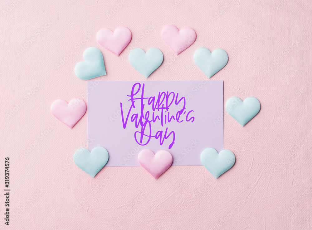 Pastel color card on pink textured background. Happy Valentine's day greetings and textile hearts