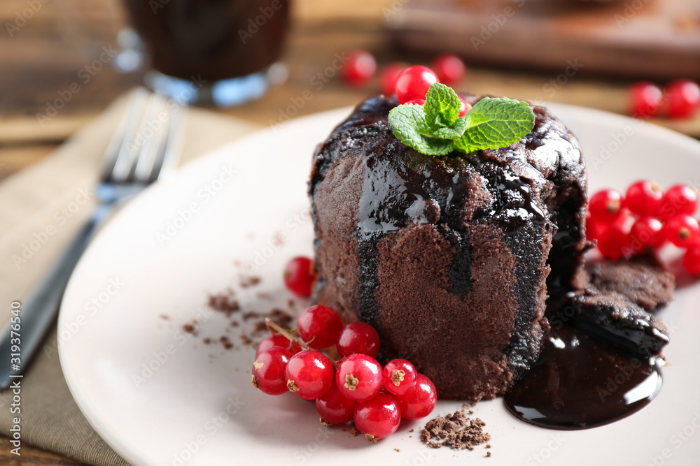 Delicious warm chocolate lava cake with mint and berries on plate, closeup