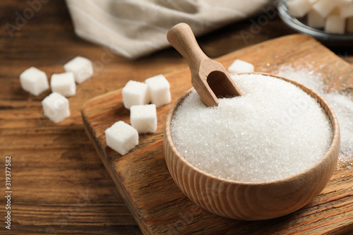 Fototapeta Granulated sugar in bowl on wooden table