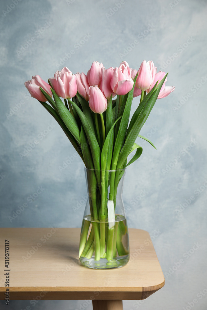 Beautiful pink spring tulips in vase on wooden table