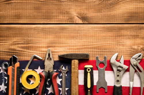 Labor day. American flag and various tools on a wooden background. The concept of labor day. Empty space for text.