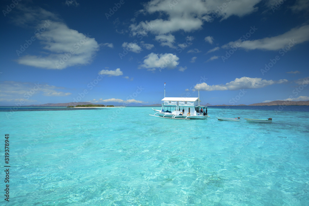 Traditional style white boat in the turquoise waters of Komodo National Park. Flores, East Nusa Tenggara, Indonesia Traditional style white boat in the turquoise waters of Komodo National Park. Flores, East Nusa Tenggara, Indonesia