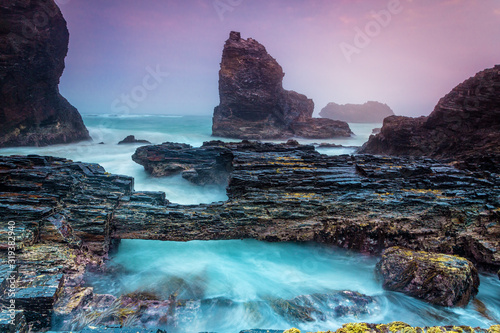 Konstfotografi Natural bridge over tidal waters along craggy coastline