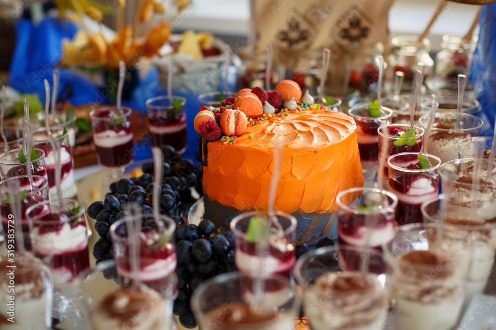 Fruit cake decorated with macaroni. Candy Bar. Sweet snacks in cups.