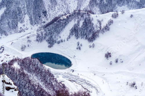 Snow-capped mountain peaks and deep gorges in the area of cross pass, Georgia. Round lake in the gorge