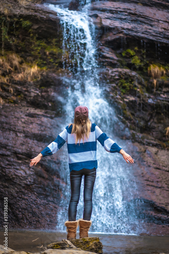 A young, fair-haired blonde with a blue and white wool sweater on her back in a waterfall. Lifestyle session