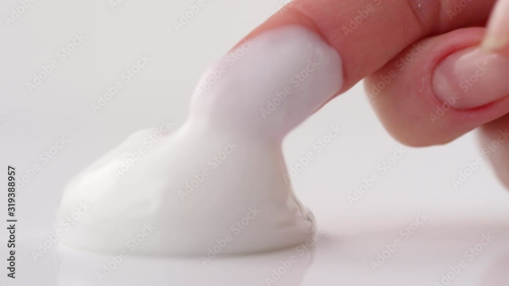 Close up studio shot of female hand of taking moisturizing cosmetic cream with finger on white background