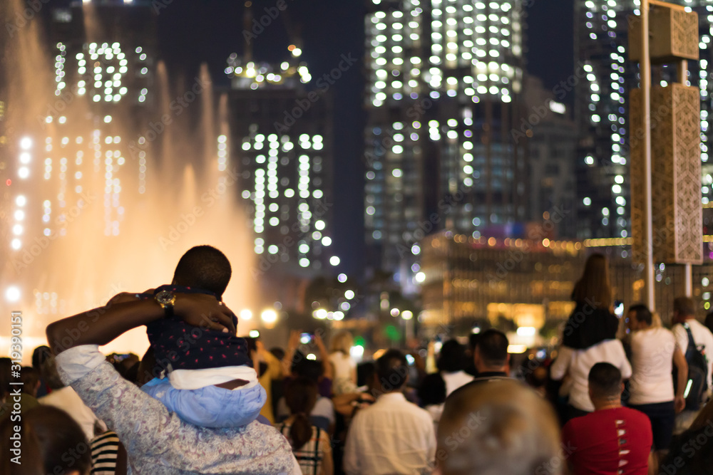 Crowd of visitors contemplating the show around the dancing fountains at night outside the Dubai Mall in the United Arab Emirates.