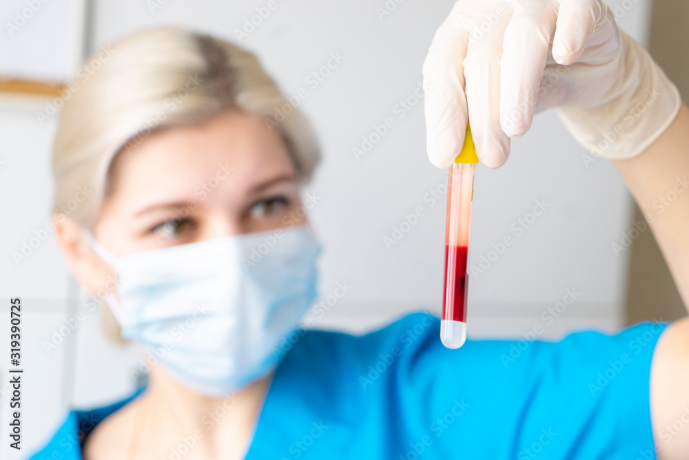 pretty caucasian nurse with face mask and latex gloves is holding test tube of blood for checking corona virus or other infections pretty caucasian nurse with face mask and latex gloves is holding test tube of blood for checking corona virus or other infections