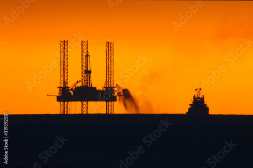 Towing of the oil platform. Oil platform at sunset with a burning torch. Drilling platform in the port.