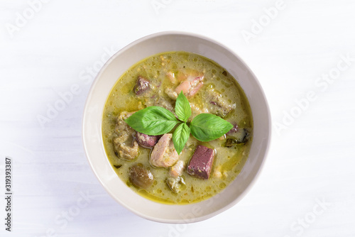 Thai green curry chicken in a bowl on white background, top view
