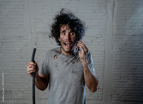 Funny man holding burnt cable calling electrician for help. DIY repairs concept photo