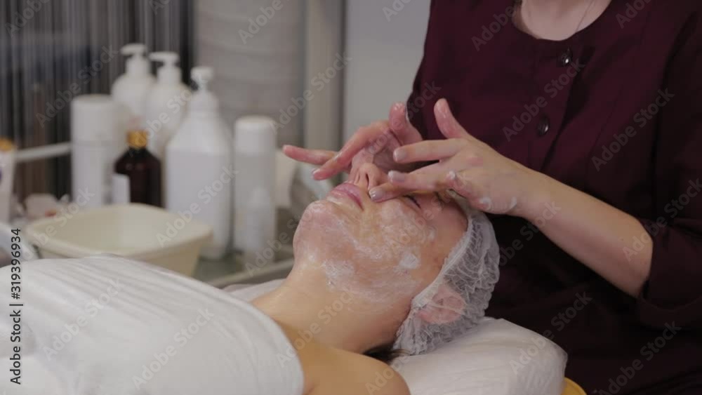 A professional beautician washes the patient's face with liquid soap and simultaneously massages. A professional beautician washes the patient's face with liquid soap and simultaneously massages.