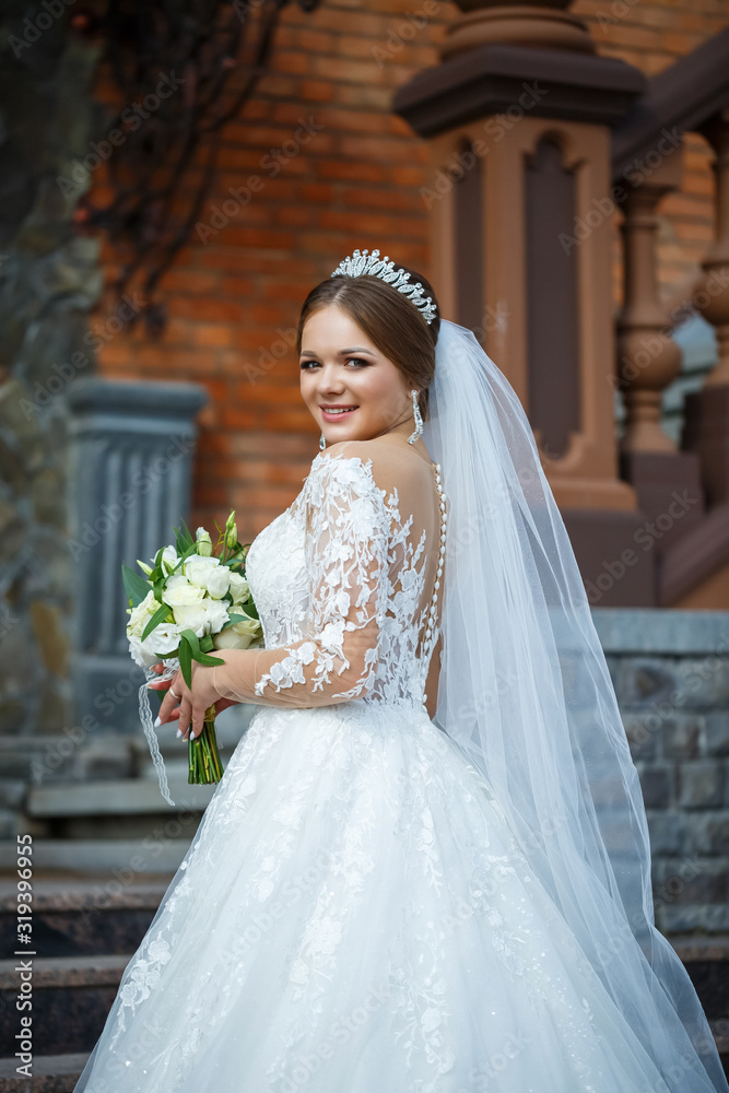 Naklejka premium bride in a white dress with a bouquet in her hands and a crown on her head