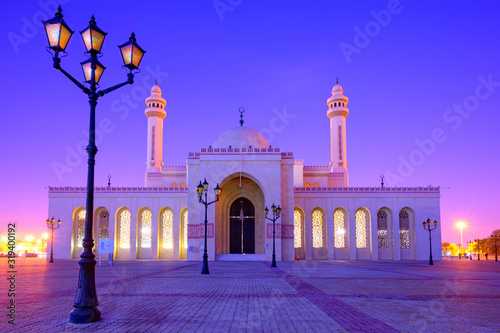 Beautiful architecture of Al Fatch Grand Mosque with lights on early morning over blue sky background, Manama Bahrain © Jantira