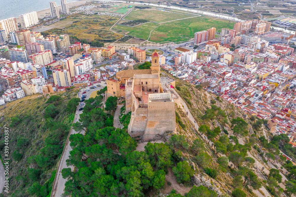 Aerial sunset view of Cullera church and castle with rectangular keep towering over the popular Spanish vacation resort town