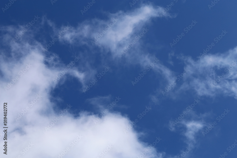 Blue sky with cute white clouds. Sunny summer day sky. Beautiful, relaxing background image that symbolizes happiness, religion and freedom. Color image.