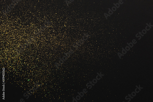 Gold glitter on black background. Holiday abstract texture