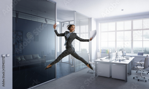 Dancing businesswoman in office. Mixed media photo