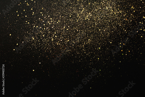 Gold glitter on black background. Holiday abstract texture