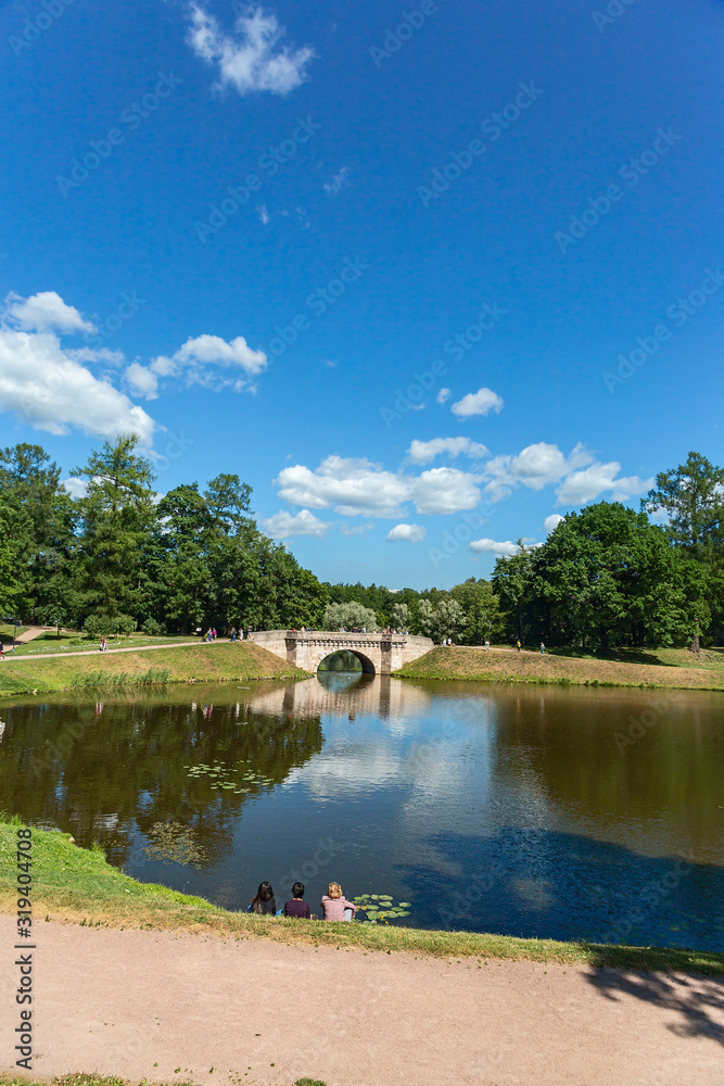 Obraz premium young girls have a rest on the shore of a picturesque pond in the suburbs of St. Petersburg, Russia
