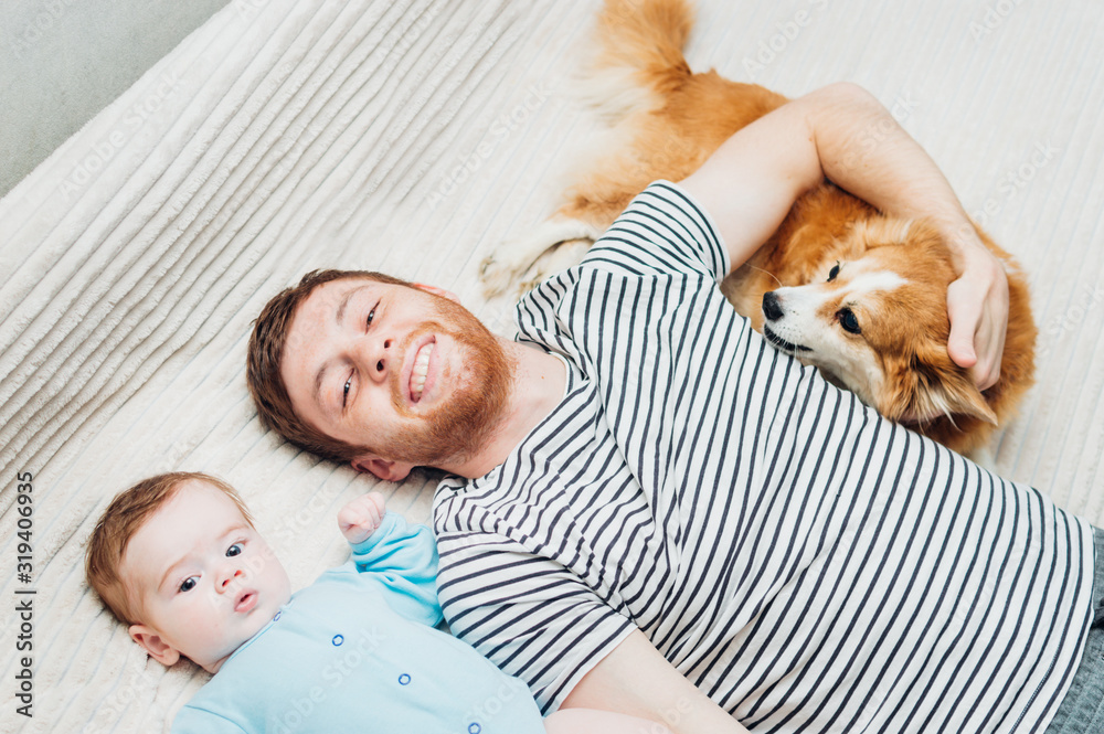 Dad and baby are lying on the bed with the dog. Close-up portrait