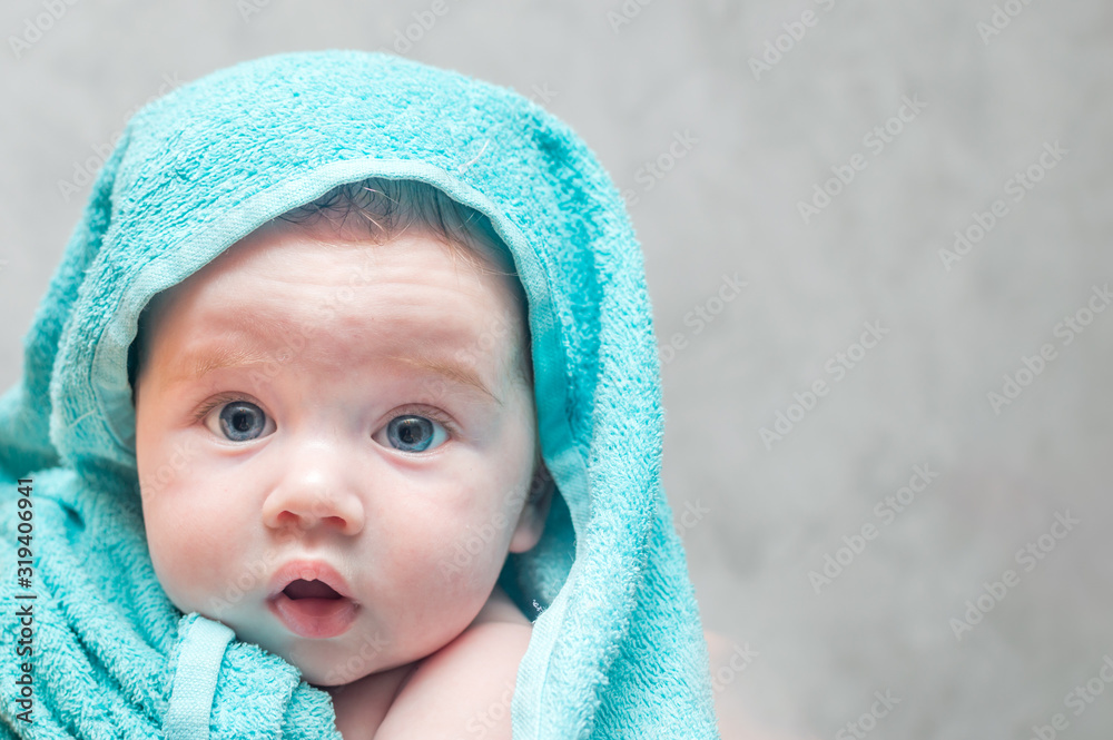 Closeup portrait of a baby in a towel after bathing. Baby Care Concept Closeup portrait of a baby in a towel after bathing. Baby Care Concept