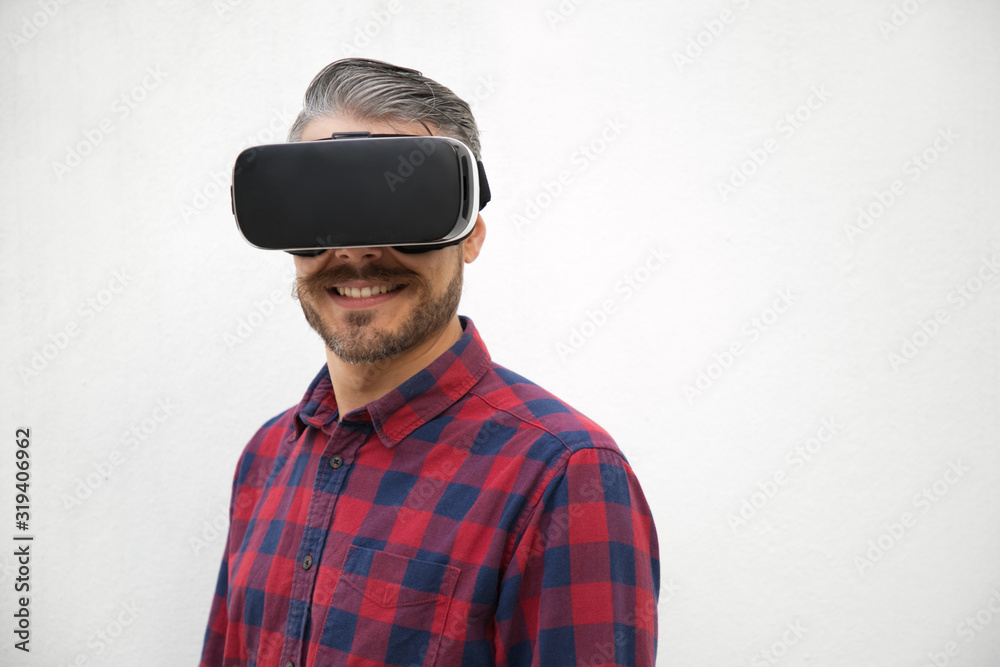 Smiling young man wearing VR glasses. Front view of cheerful guy with new modern device. Technology concept Smiling young man wearing VR glasses. Front view of cheerful guy with new modern device. Technology concept