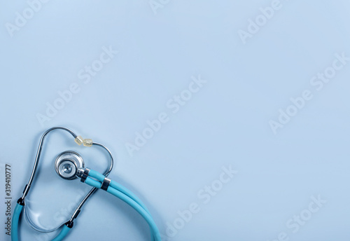 Blue medical stethoscope on a blue background, top view, copy space
