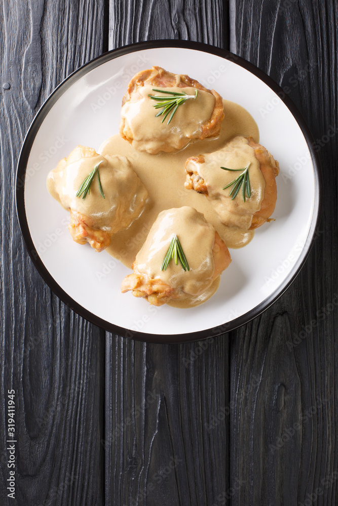 Chicken thighs in a sauce of Dijon mustard and maple syrup in a plate close-up. Vertical top view Chicken thighs in a sauce of Dijon mustard and maple syrup in a plate close-up. Vertical top view