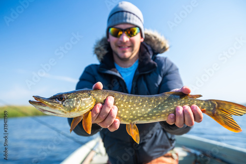 Young fisherman holds the pike fish