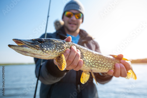 Young fisherman holds the pike fish photo