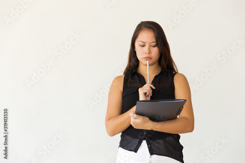 Serious female student with folder and pen. Front view of focused young Asian woman holding folder and pen isolated on white background. Education concept