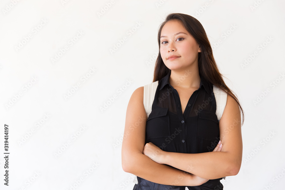 Confident young woman with backpack looking at camera. Portrait of beautiful young female college student standing with crossed arms and looking at camera. Education concept Confident young woman with backpack looking at camera. Portrait of beautiful young female college student standing with crossed arms and looking at camera. Education concept