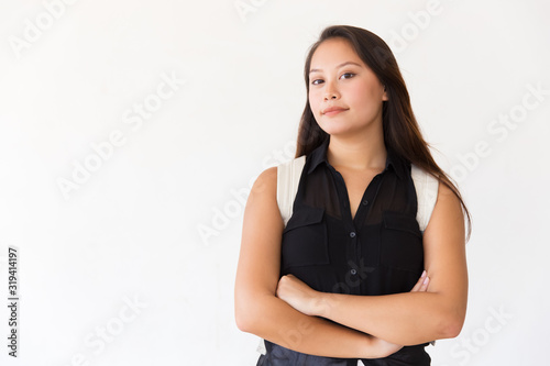 Confident young woman with backpack looking at camera. Portrait of beautiful young female college student standing with crossed arms and looking at camera. Education concept © Mangostar