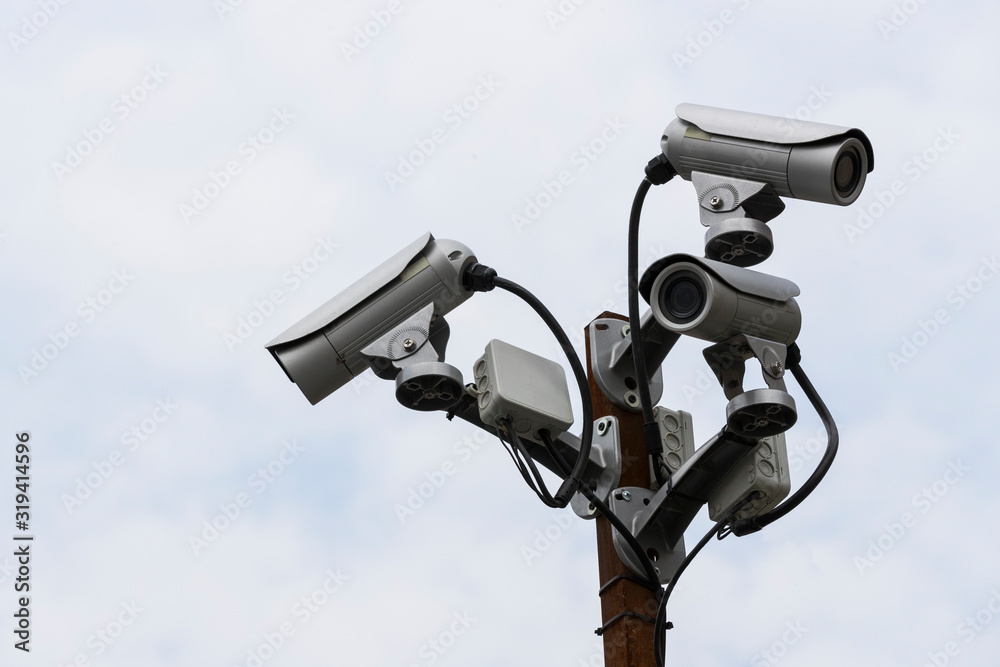 A group of surveillance cameras on a sky background. A group of surveillance cameras on a sky background.